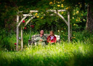 two visitors relaxing on a wooden swing seat at abbotsbury subtropical gardens